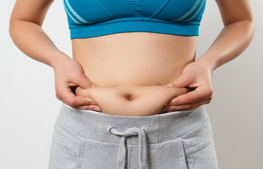 the woman presses her fingers to the folds of fat on the sides of her stomach