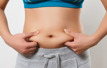 Naklejka premium the woman presses her fingers to the folds of fat on the sides of her stomach
