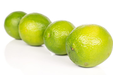 Group of four whole sour green lime diagonal isolated on white background