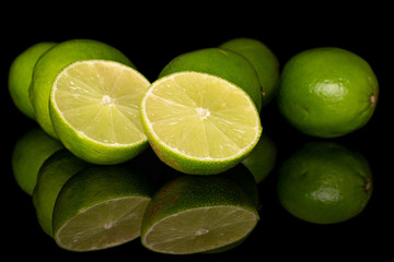Group of five whole two halves of sour green lime isolated on black glass