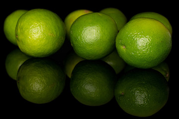 Group of seven whole sour green lime isolated on black glass