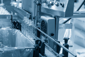 The PET bottles on the conveyor belt for filling process in the drinking water factory. The drinking water factory production process by automatic filling machine in the plant.