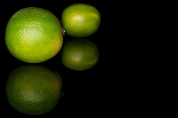 Group of two whole sour green lime isolated on black glass