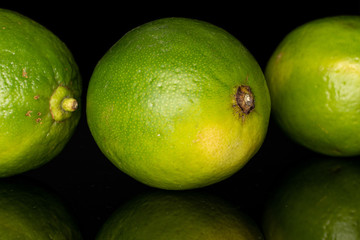 Group of three whole sour green lime isolated on black glass
