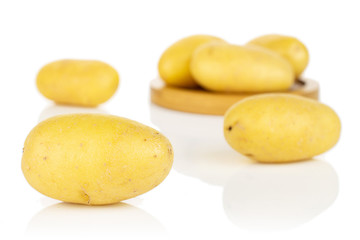 Group of six whole pale yellow potato on bamboo coaster isolated on white background