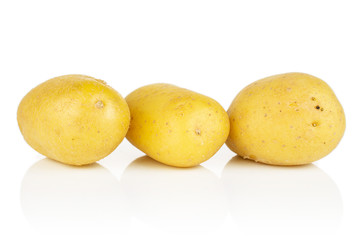 Group of three whole pale yellow potato in row isolated on white background