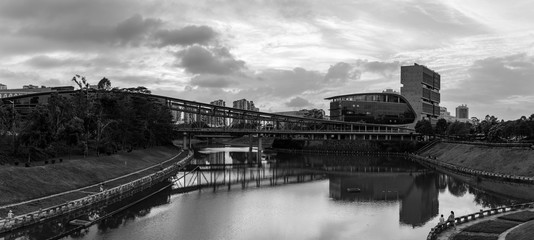 a monochrome panorama of an artistic bridge over the river, shot in a university campus of shenzhen china