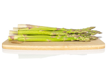 Lot of whole healthy green asparagus on bamboo cutting board isolated on white background