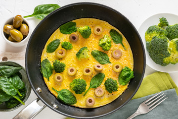Omelette with broccoli, spinach and olives in a pan. Frittata - italian omelet with green vegetables.