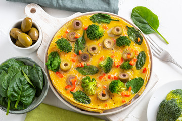 Omelette with broccoli, spinach and olives on a plate. Frittata - italian omelet with green vegetables.