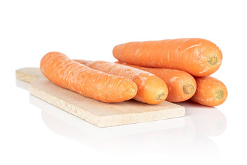 Group of five whole fresh orange carrot on wooden cutting board isolated on white background
