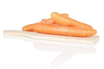 Lot of whole fresh orange carrot on wooden cutting board isolated on white background