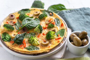 Omelette with broccoli, spinach and olives on a plate. Frittata - italian omelet with green vegetables.