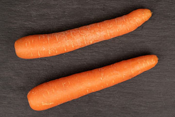Group of two whole fresh orange carrot flatlay on grey stone