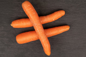 Group of three whole fresh orange carrot flatlay on grey stone