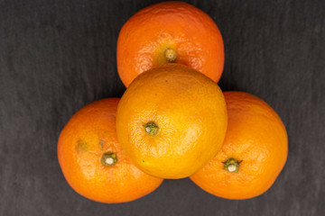 Group of four whole fresh orange mandarin flatlay on grey stone