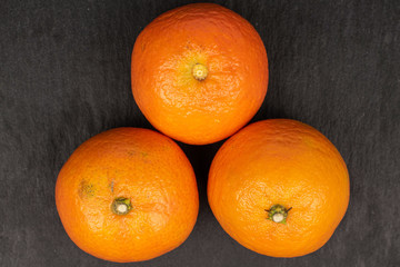 Group of three whole fresh orange mandarin flatlay on grey stone