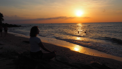 girl meditating practising yoga at the beach kimono thailand sunset