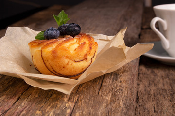 Blueberry muffin and berries with a cup of tea on an old wooden board