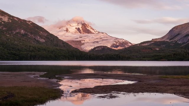 Time lapse of a sunrise at a Ilon lagoon with mount Tronador behind. Clouds moving around a mountaintop with reflection on water in the morning. Pampa Linda, Bariloche, Río Negro, Patagonia Argentina