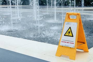 Caution wet floor sign on tile floor fountain area, Warning to walk carefully in this area.