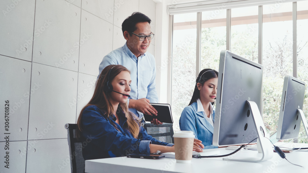 Poster customer support agent or call center with headset works on desktop computer while supporting the cu