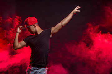 professional male dancer dancing isolated over smoky background, with hands up