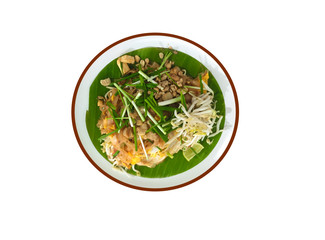 pad thai with pork  tofu bean sprouts peanuts and lime garnish on banana leaf and white background.