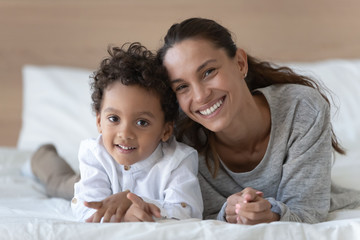 Happy smiling young woman lying on bed with son.