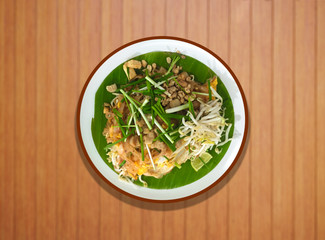 pad thai with pork  tofu bean sprouts peanuts and lime garnish on banana leaf and white background.