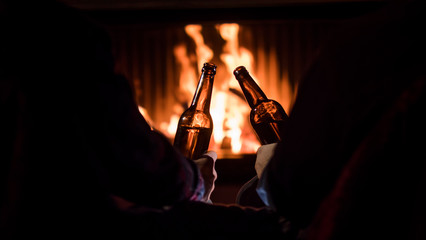 Winter escape - men relax by the fireplace with beer in their hands