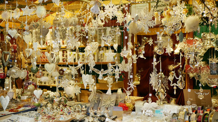 Christmas market stall or stand with tree decorated ornaments products angel, star, toys, balls, garlands, various, ornaments, and animals are hanged pine needles. decoration hanging traditional