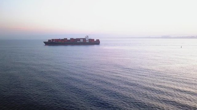 Large container ship at sea, loaded with various container brands. ULCV container ship sails on open water fully loaded with containers and cargo.
