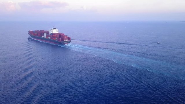 Large container ship at sea, loaded with various container brands. ULCV container ship sails on open water fully loaded with containers and cargo.