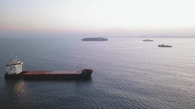 Aerial pass over a large Cargo Ship anchored at sea.