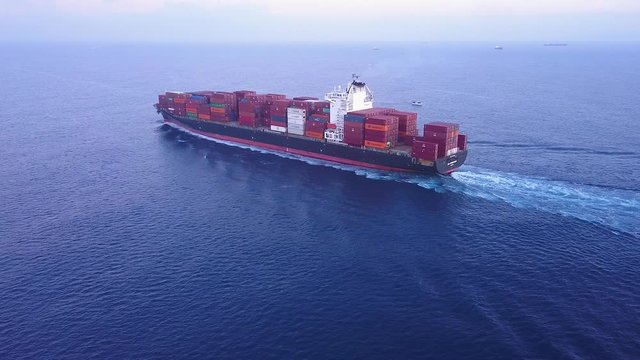 Large container ship at sea, loaded with various container brands. ULCV container ship sails on open water fully loaded with containers and cargo.