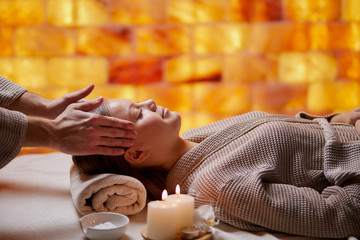 Good-looking young woman in bathrobe have massage o face by professional female in spa salon. Lying down on desk