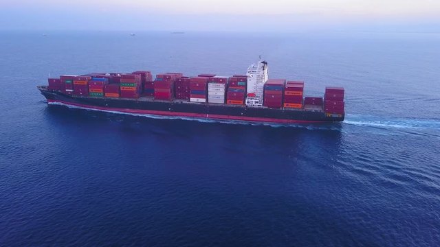 Large container ship at sea, loaded with various container brands. ULCV container ship sails on open water fully loaded with containers and cargo.