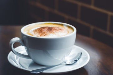 close up modern hot black coffee the cappuccino on wood background with coffee bubble foam pattern and texture in white cup looking and feel so delicious on glasses table in coffee shop.