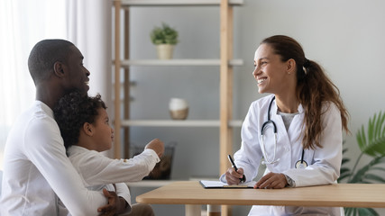 Happy african american man visiting friendly female pediatrician with son. - obrazy, fototapety, plakaty