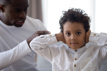 Little mixed race preschool boy covering ears with hands.