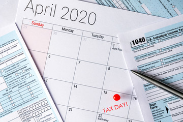 April 2020 calendar with the 15th pinned with tax day text, and 1040 tax forms on the sides.