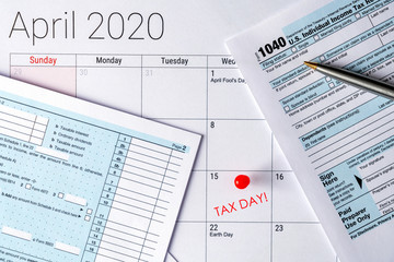 Naklejka na ściany i meble April 2020 calendar with the 15th pinned with tax day text, and 1040 tax forms on the sides.