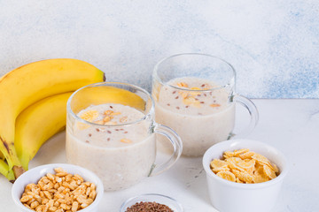 Banana smoothie in cups, flax seeds, cocoa, oatmeal and puffed rice on a white background. Healthy eating concept