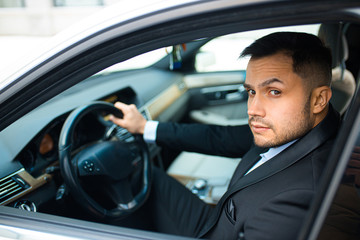 Fototapeta na wymiar young bearded male behind wheel in his executive car, driving car