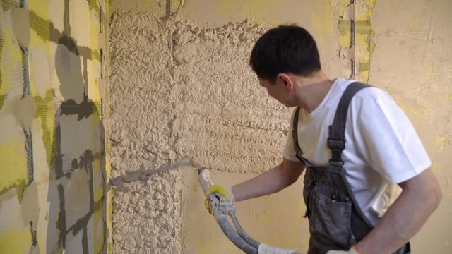 Plastering mortar machine. Automatic plaster. Repairing or renovating house or apartment. Builder at construction professional