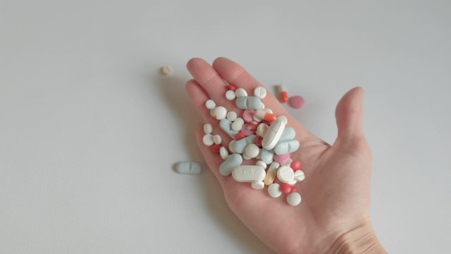 Woman holding pills in hand, concept of medicine and medication misuse and overdose