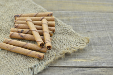 Chocolate wafer roll sticks on raw cloth on wooden table