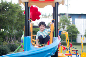 Young asian boy playing on a blue playground slide