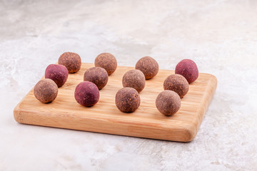 Homemade Raw Vegan Cacao Energy Balls on Wooden Tray on White Marble Background. Healthy Chocolate Sweets from Nuts and Dates. Concept of Natural Vegetarian Handmade Dessert